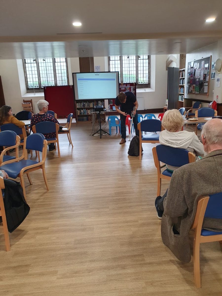 Euan presenting the Smart Walking Stick to members of the Parkinson's UK Southend support group, who are seated and watching the demonstration